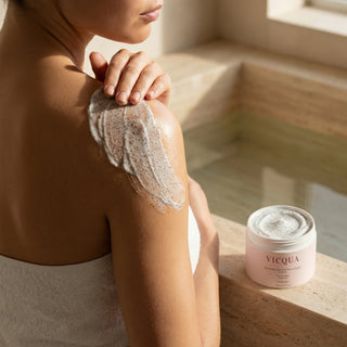 Woman applying Vicqua Icelandic Volcano Face & Body Scrub before bath in luxury bathroom